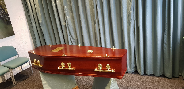 Mahogany veneer coffin with Oscar bar furnishings at Jason O'Brien & Family Funeral Services Limited in Ashton-Under-Lyne, Greater Manchester