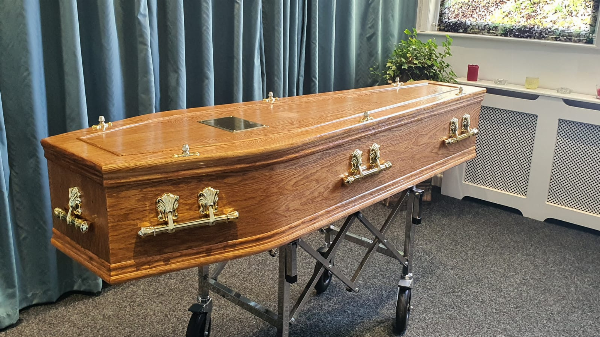 Medium stain oak veneer coffin with double moulding on the lid and base and a slim trim of beading on the lid. Available at Jason O'Brien & Family Funeral Services Limited in Ashton-Under-Lyne, Greater Manchester